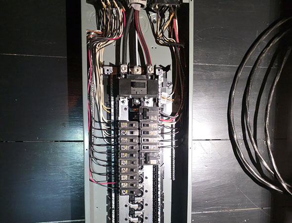 An overhead view of an electrical panel showing multiple circuit breakers and numerous connected wires.